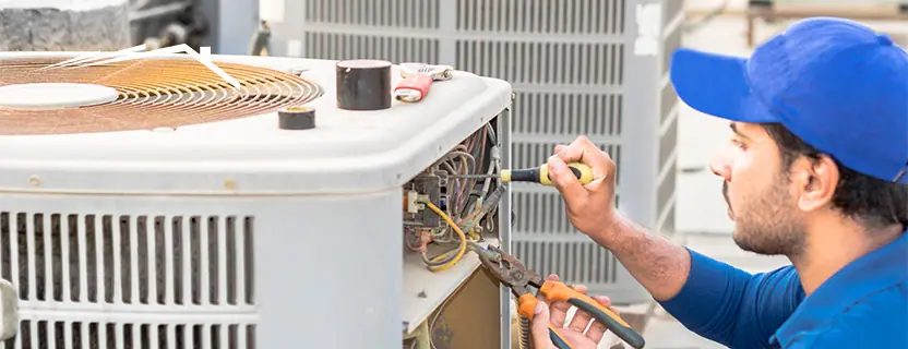 Technician repairing the electrical panel of an outdoor air conditioning condenser