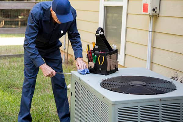 Technician inspecting a residential outdoor air conditioning condenser