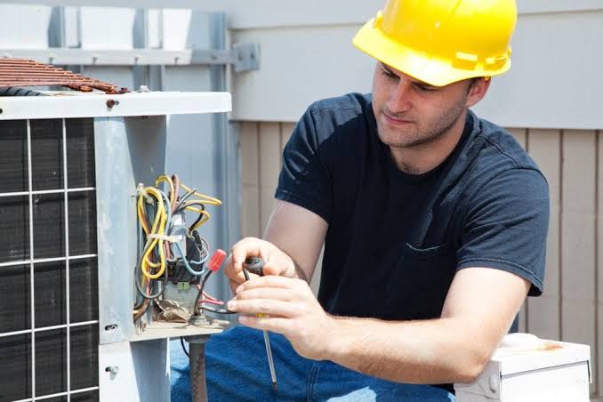 Technician repairing wiring on an outdoor air-conditioning unit