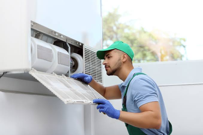 Technician sliding a dusty filter out of a wall-mounted indoor unit