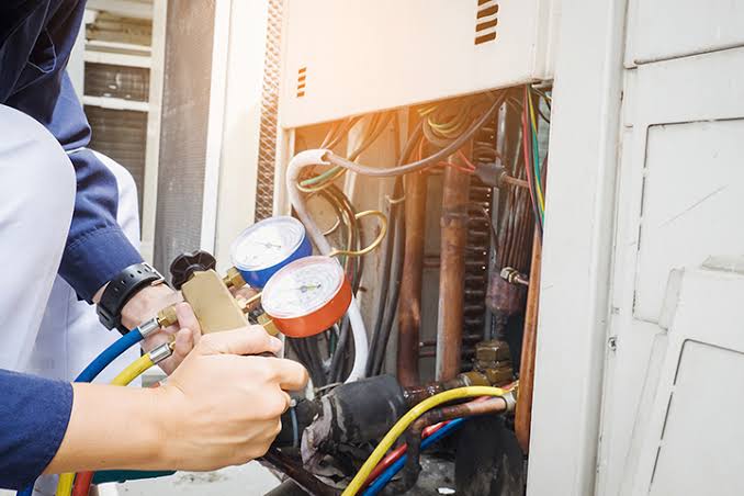 Technician checking refrigerant gauges on heating and cooling equipment