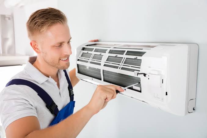 Technician adjusting the interior of a wall-mounted indoor air handler