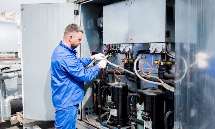Technician servicing compressors and valves on commercial HVAC equipment
