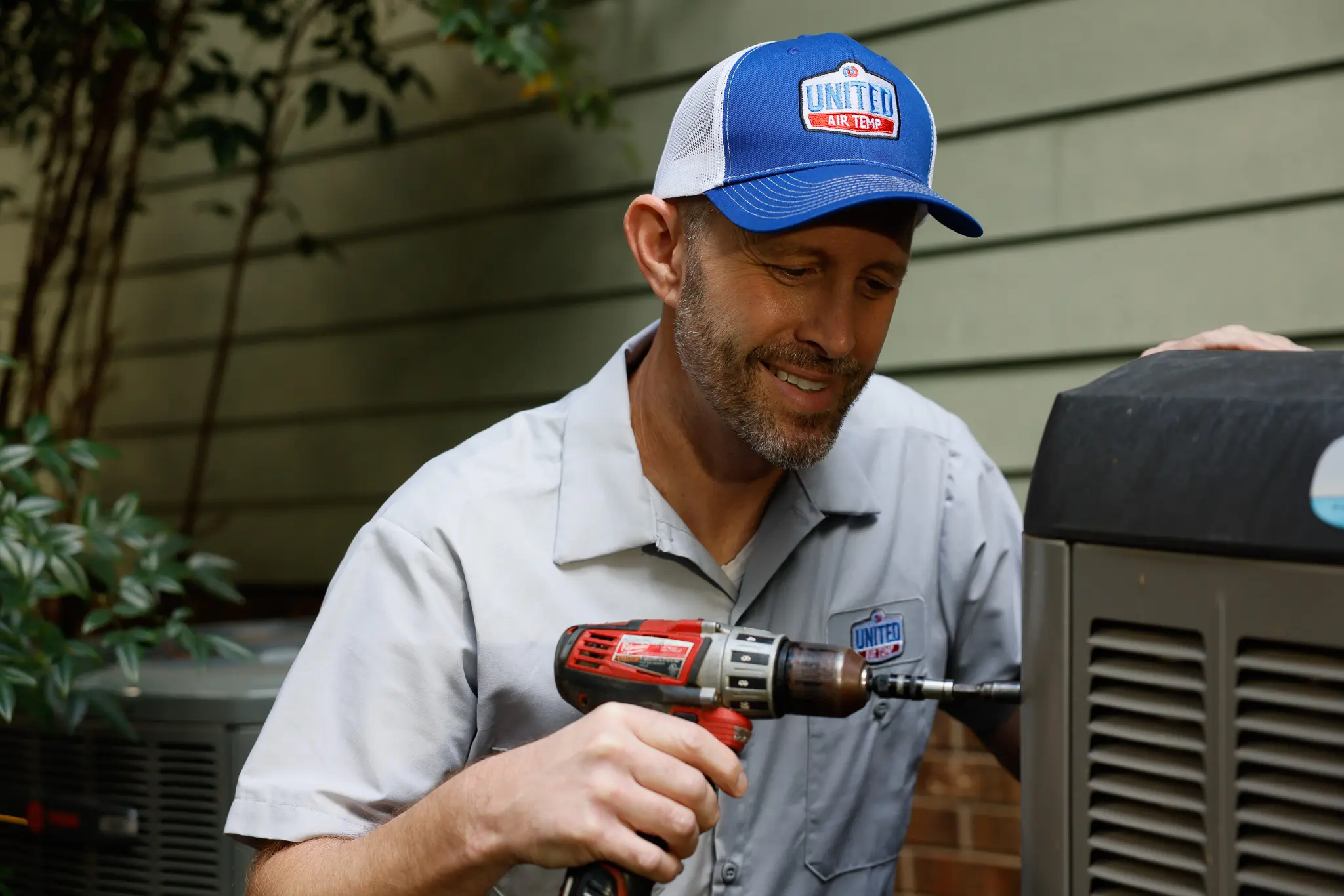 HVAC technician servicing a residential outdoor heating and cooling unit